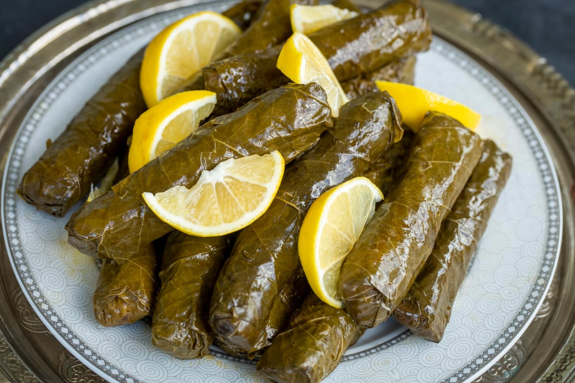 Delicious dolma (sarma) stuffed grape leaves rice, white yogurt sauce. Lebanese dolma sarma on plate. Lebanon turkish greek middle eastern cuisine. (Turkish name; Yaprak sarma)